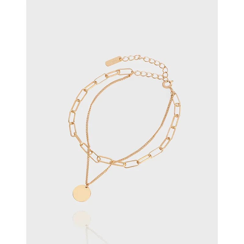 Polished sterling silver layered bracelet with a round disc pendant and adjustable extender on a light background.
