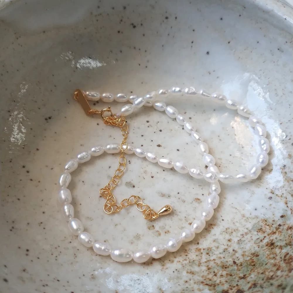 Close-up of a pearl bead necklace on a polished silver chain with an adjustable extender