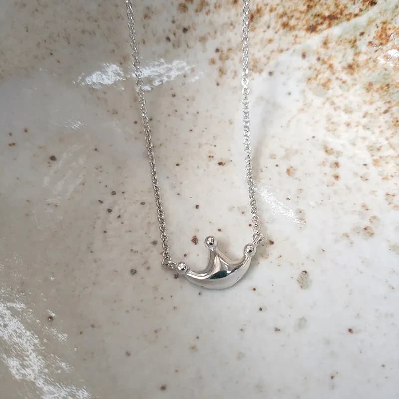 Delicate sterling silver crescent pendant with crown tips on a fine chain