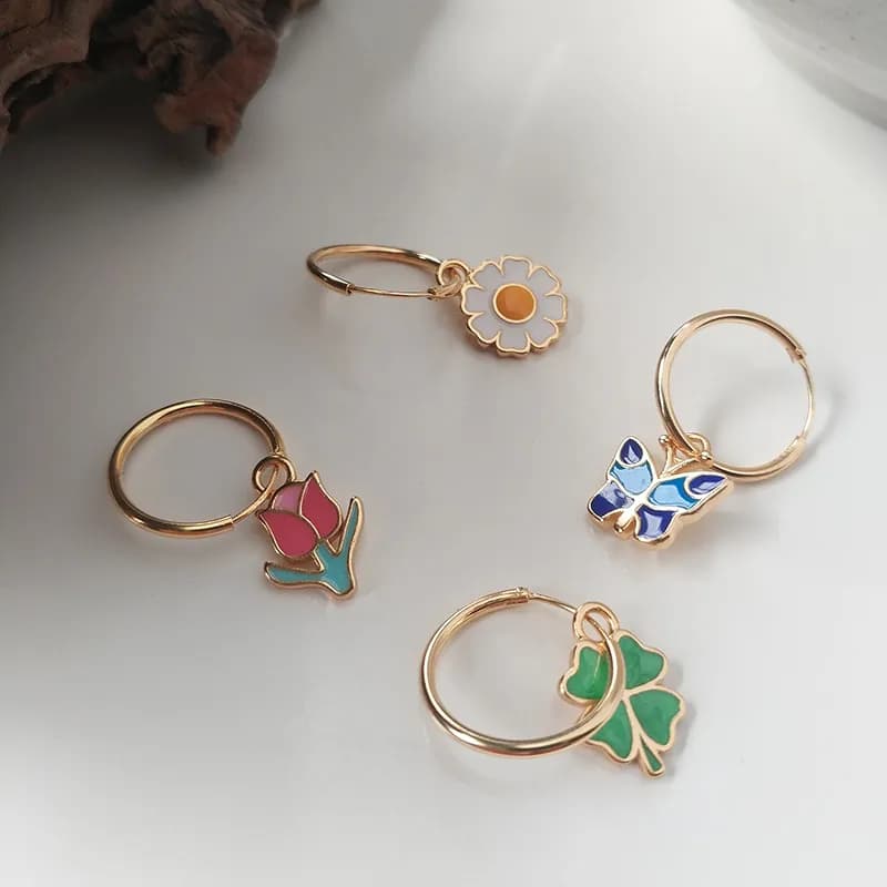 Polished sterling silver hoop earring with a small enamel flower charm