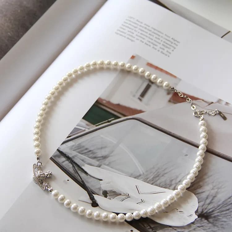 A single strand of white pearls with a polished silver clasp on an open book