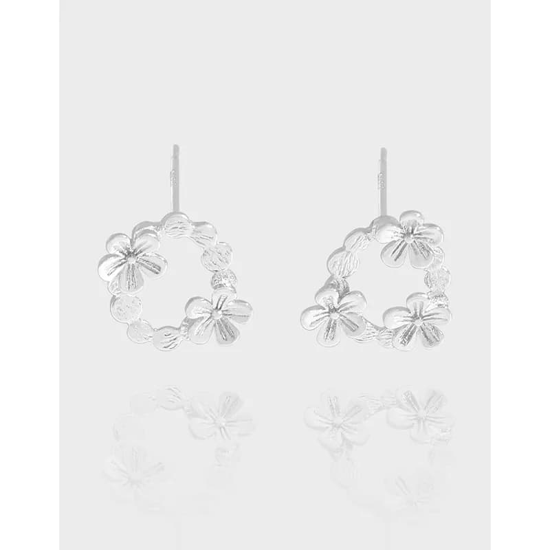 Polished sterling silver floral hoop earrings with six-petal blossoms forming a circular hoop.