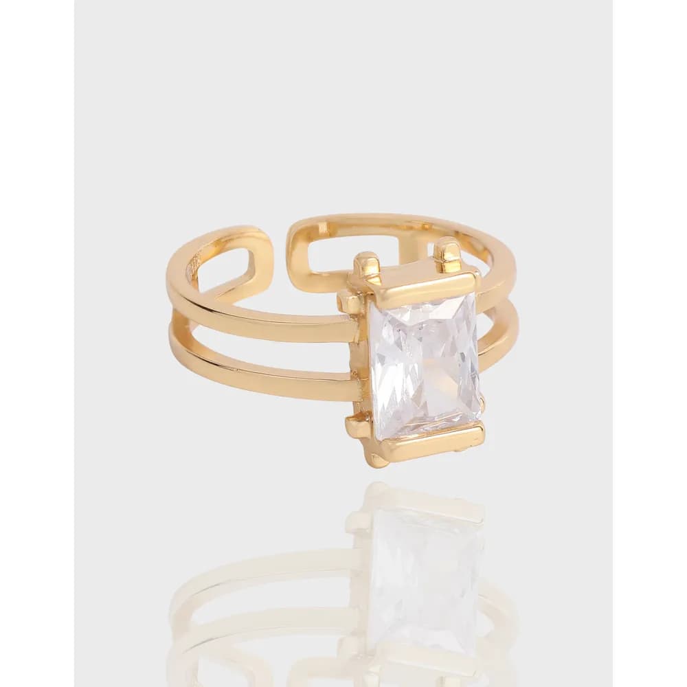 Gold-tone ring with a rectangular emerald-cut clear stone set in a double-band style.