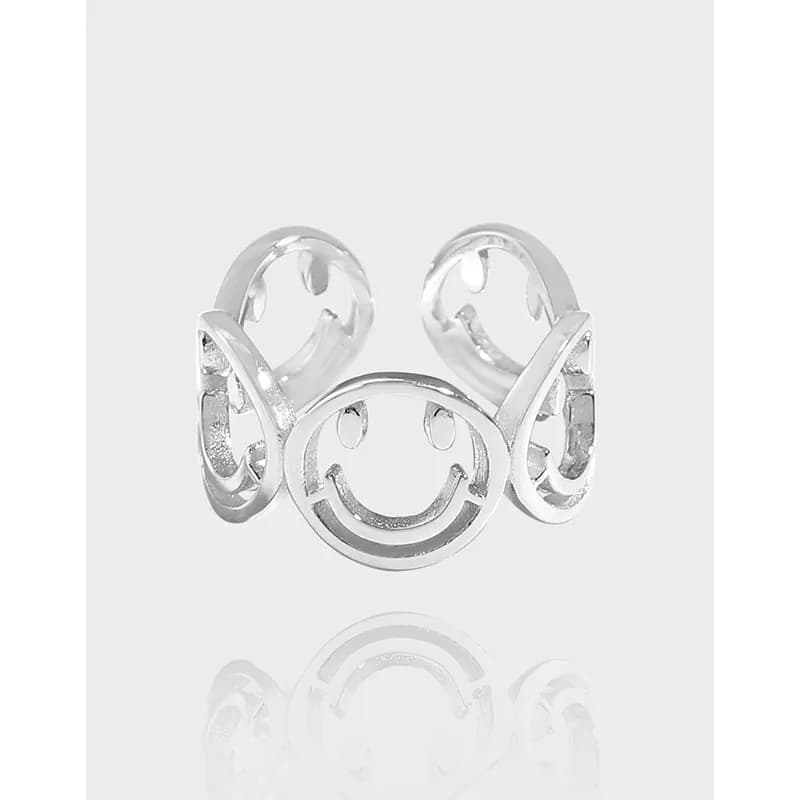 Polished sterling silver ring with a circular smiley-face motif and open-band design.