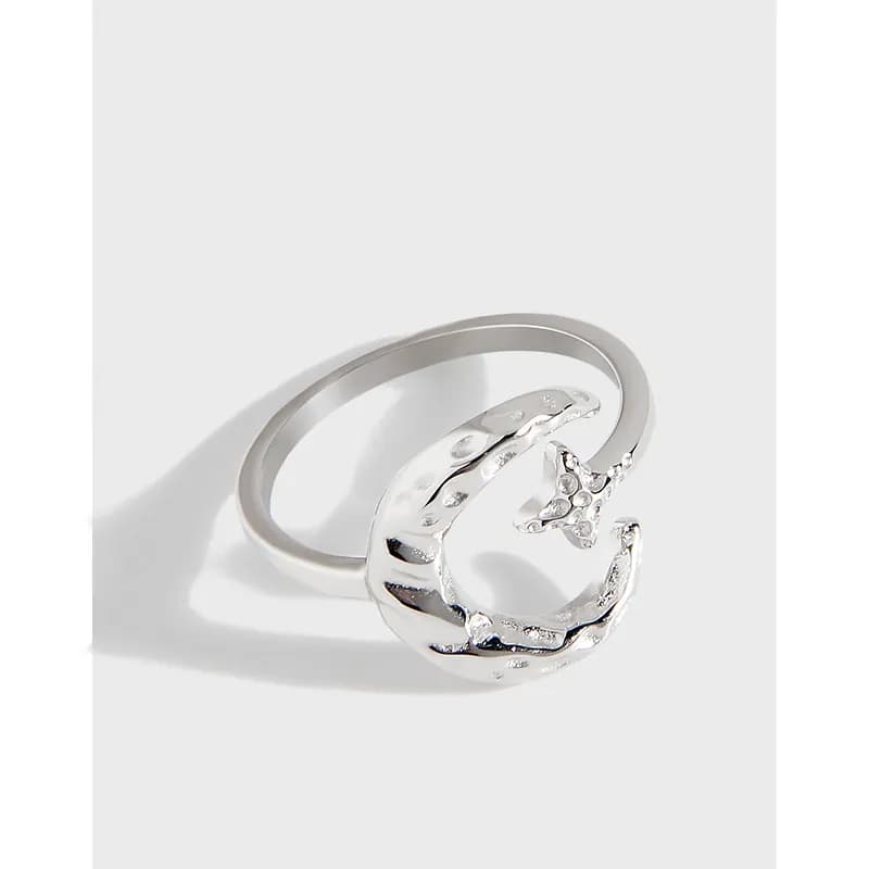 Polished sterling silver open crescent ring with organic texture and cutouts on a white background.