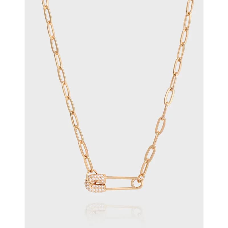 Close-up of a delicate sterling silver necklace with a crystal-studded clasp and enamel detail on a light background.