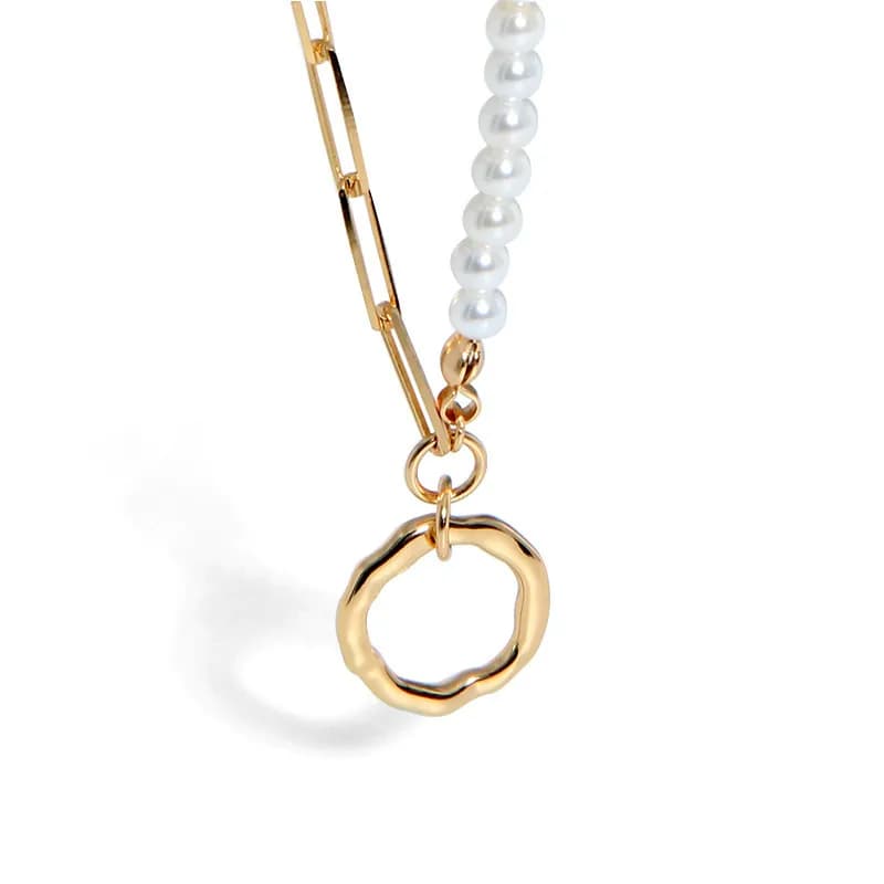 Close-up of a pearl bead necklace with a hammered gold-toned ring pendant and a slim chain