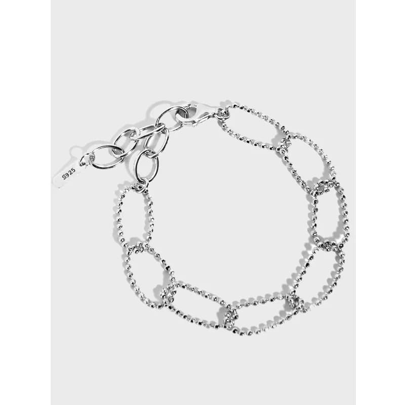 Polished sterling silver bracelet with bead-embellished oval links laid flat against a light background.