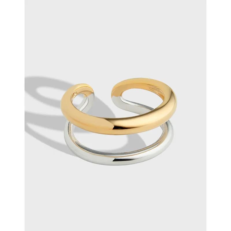 Polished two-tone interlock ring with gold and silver bands intertwined on a neutral background.