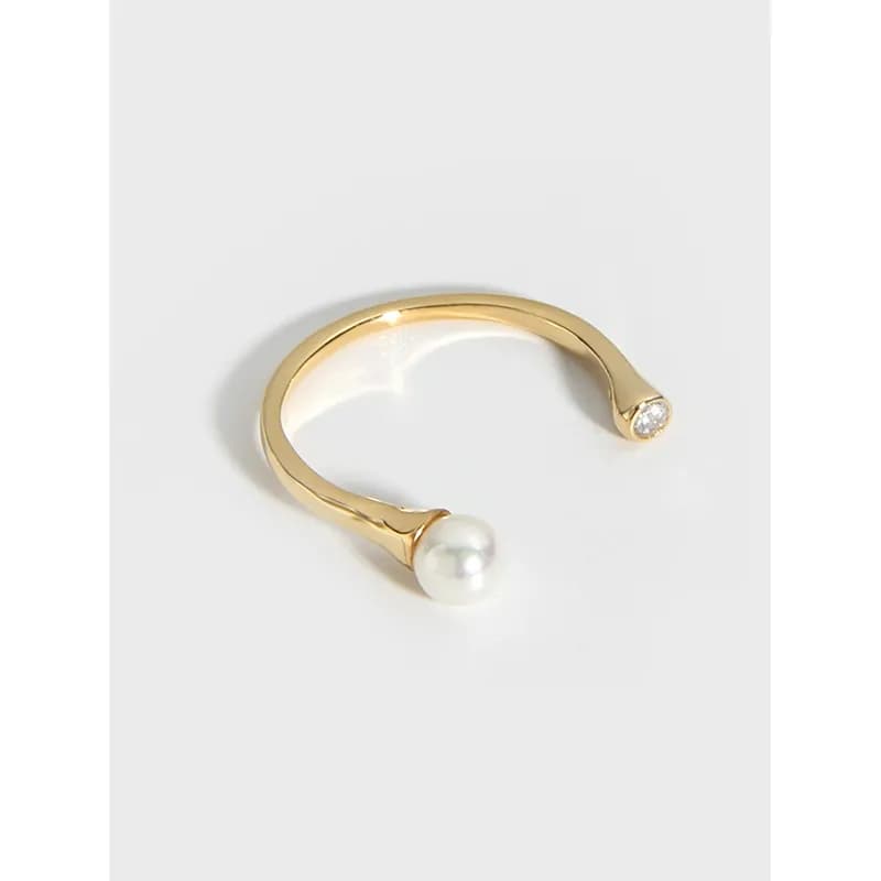 Open curved ring in gold-tone metal with a pearl on one end and a diamond on the opposite end.