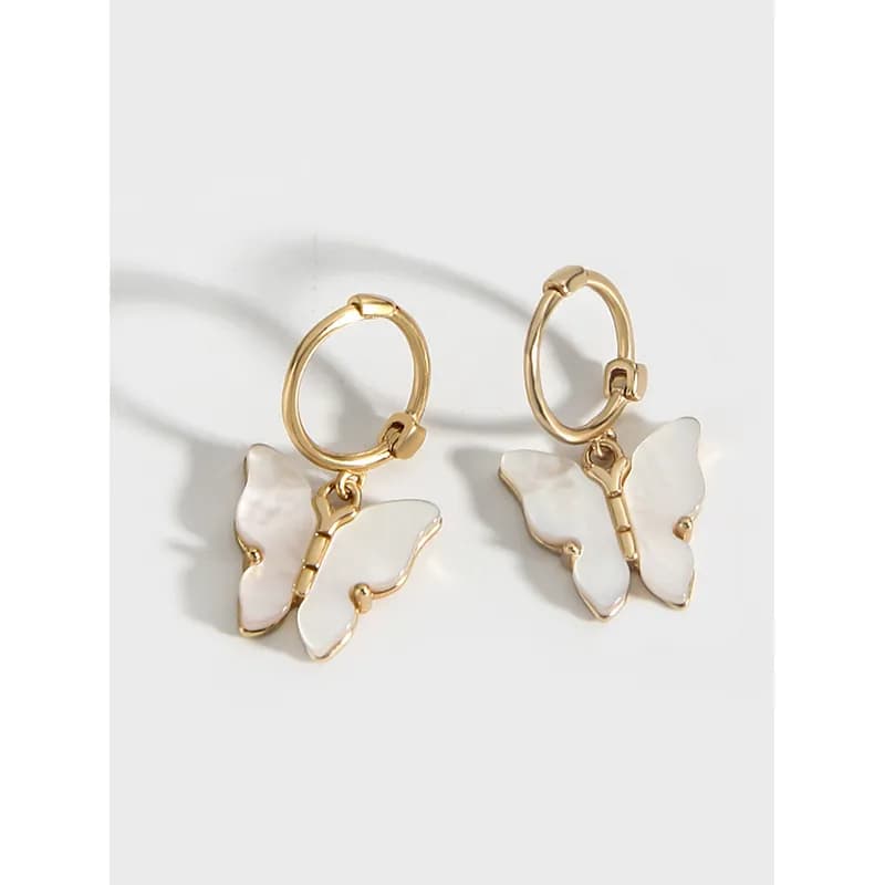 Polished sterling silver hoop earrings with white enamel butterfly charms hanging from each hoop.
