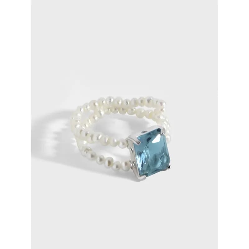 Sterling silver ring with two beaded bands and a square blue gemstone in a prong setting.