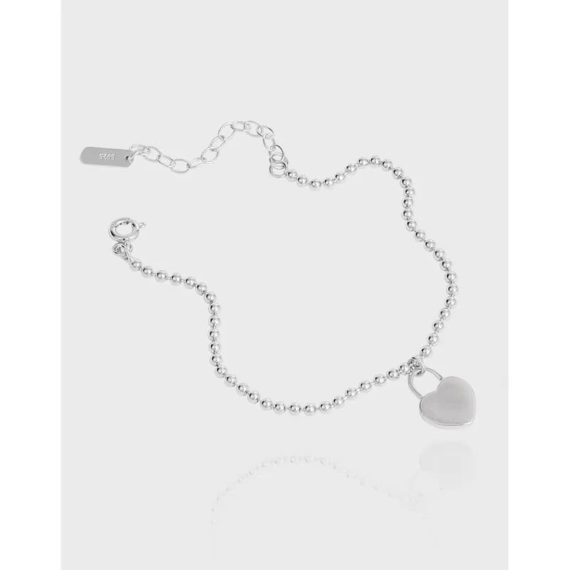 Sterling silver bead-chain bracelet with a heart charm on a light background.
