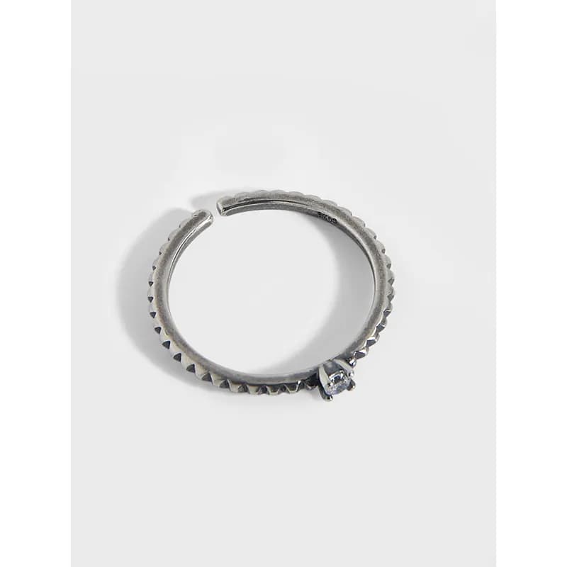 Polished sterling silver scalloped edge ring with a small solitaire gemstone on the outer side.