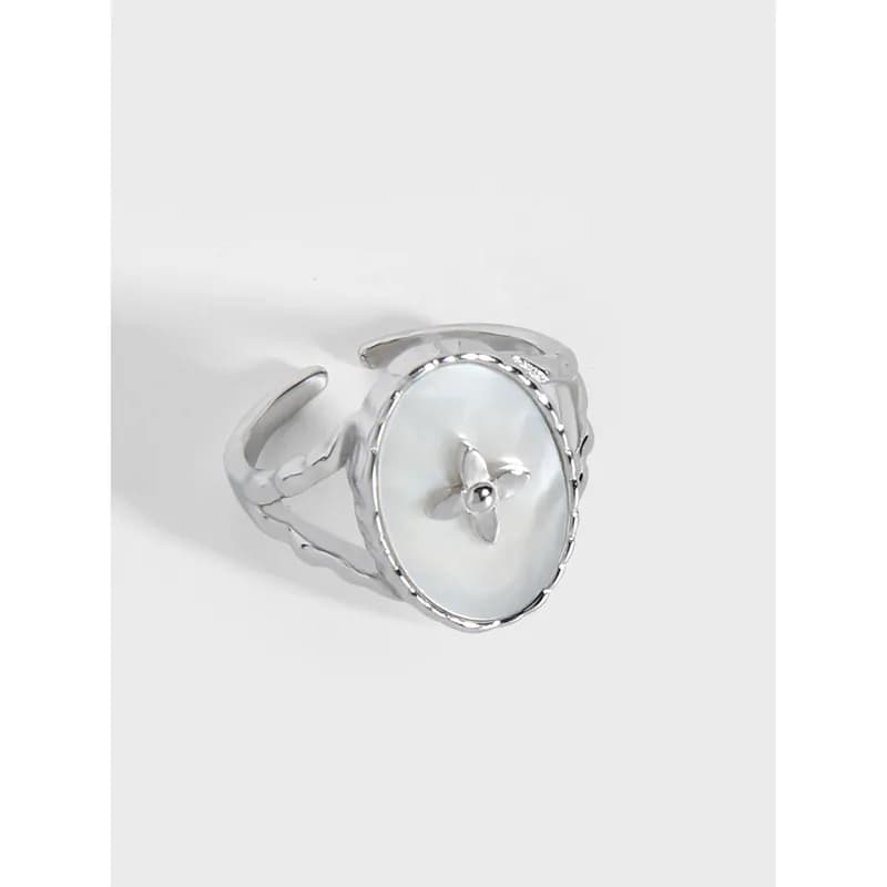 Polished sterling silver ring with a large circular mother-of-pearl disc and rope-edge bezel on an open adjustable band.