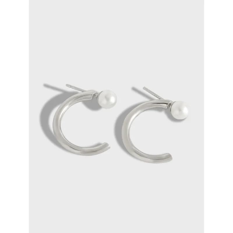 Polished sterling silver crescent hoop earrings with a pearl accent on the outer rim.