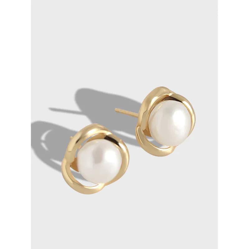 Close-up of polished sterling silver earrings with white pearls framed by circular hoops, shown as a pair with posts.