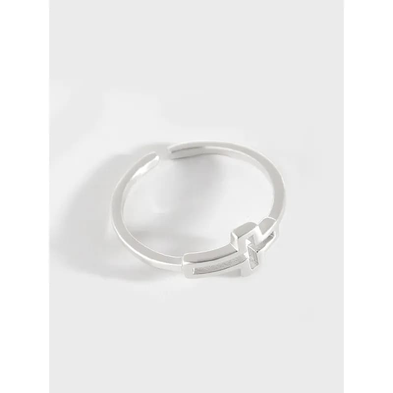Polished sterling silver ring with an X-shaped motif on a light background.