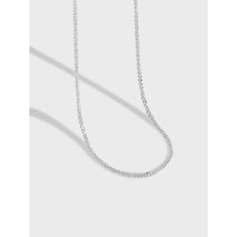 Close-up of a polished sterling silver pavé bead chain necklace laid in a gentle curve.