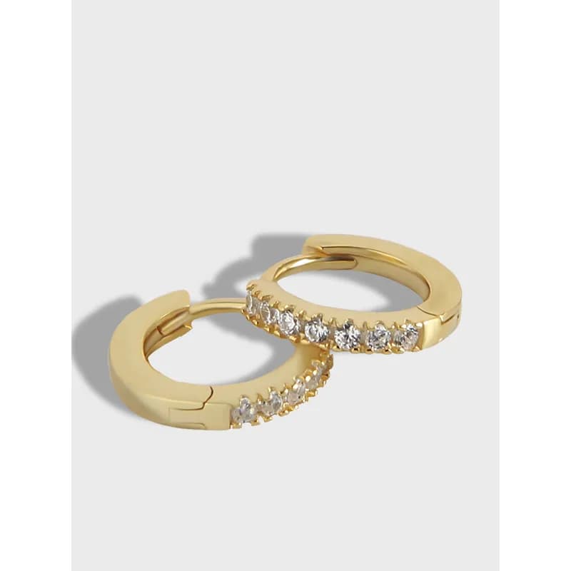Two gold-tone pavé hoops with a row of stones along the outer edge, resting on a light background.