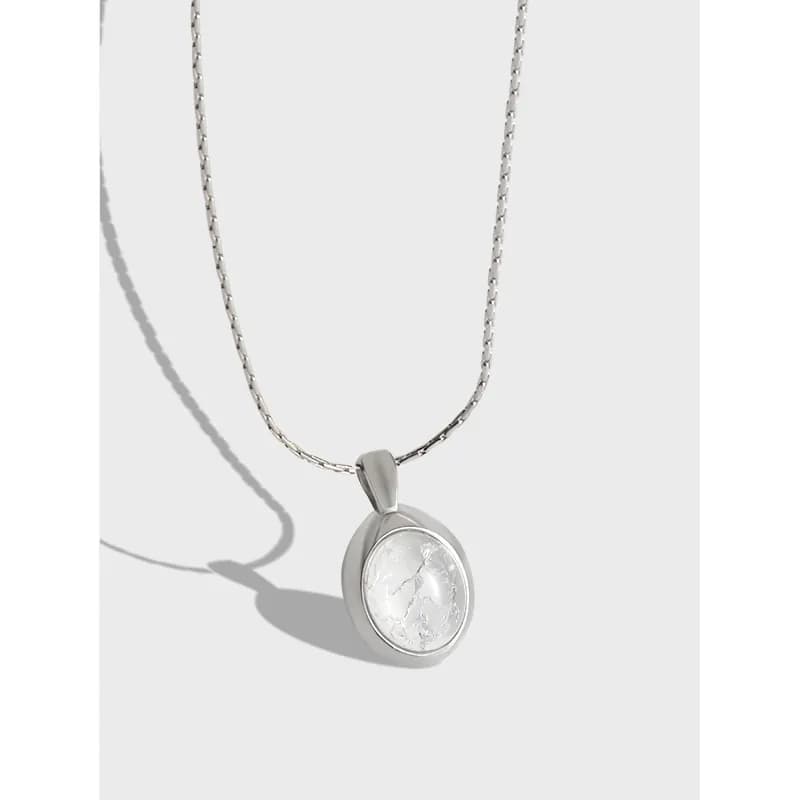 Polished sterling silver necklace with a circular bezel pendant containing a white veined stone.