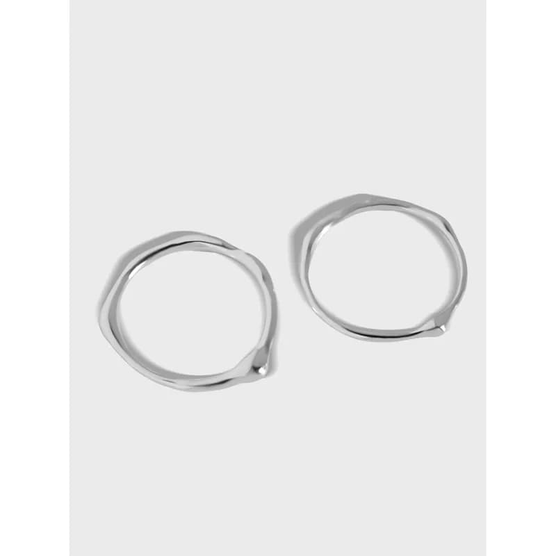 Two polished sterling silver organic circle rings with irregular shapes on a light background.