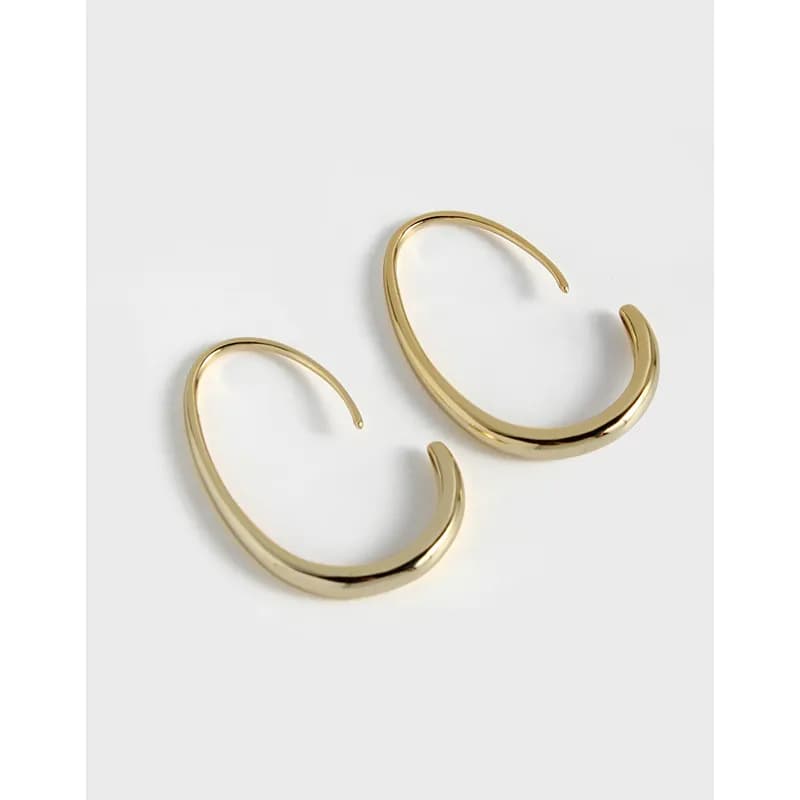 A pair of polished crescent-shaped hoop earrings in sterling silver laid flat.