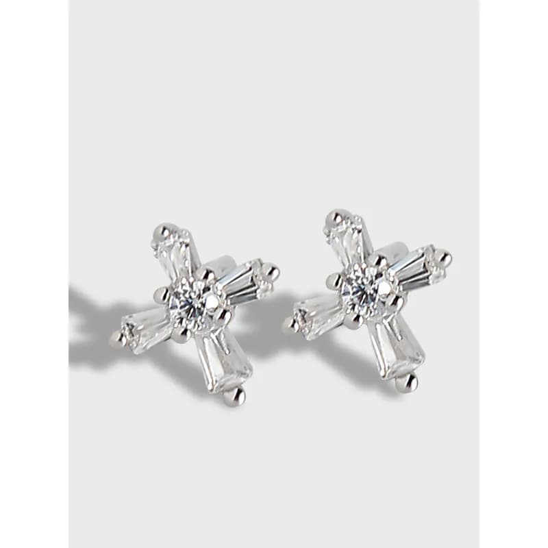 Sterling silver cross-shaped stud earrings with clear stones on a light background.
