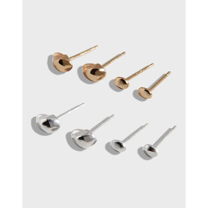 Close-up of domed disc stud earrings in silver and gold tones on posts