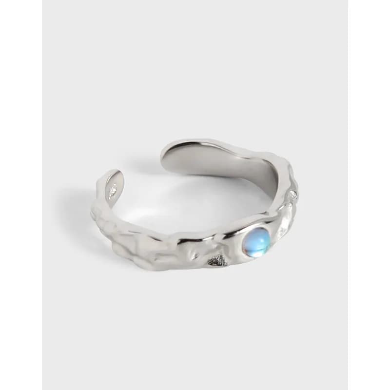 Polished sterling silver ring with an irregular textured band and a small blue cabochon on the outer edge.