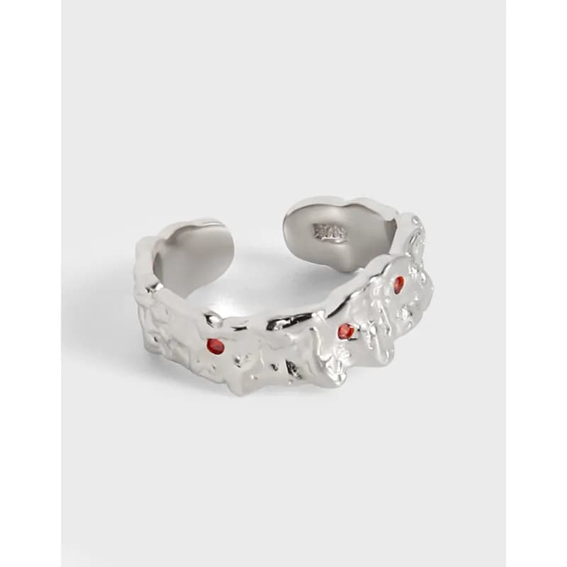 Polished sterling silver textured ring with irregular coral-inspired facets and small red stones.