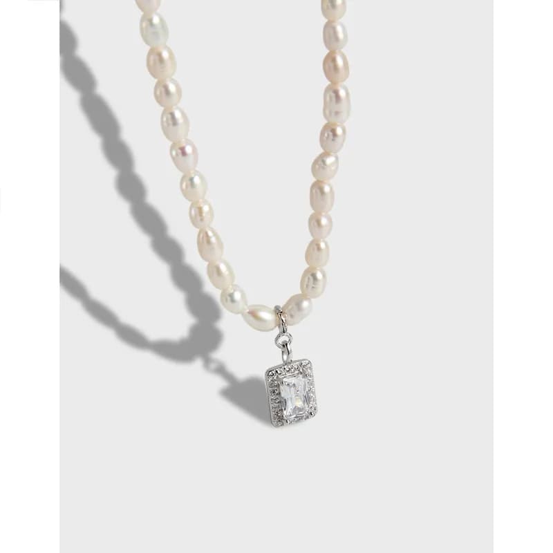 Sterling silver pearl bead necklace with rectangular halo pendant hanging at center front.