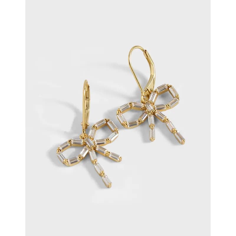 Polished silver-toned earrings with a crystal baguette bow design, dangling from lever-back hooks.