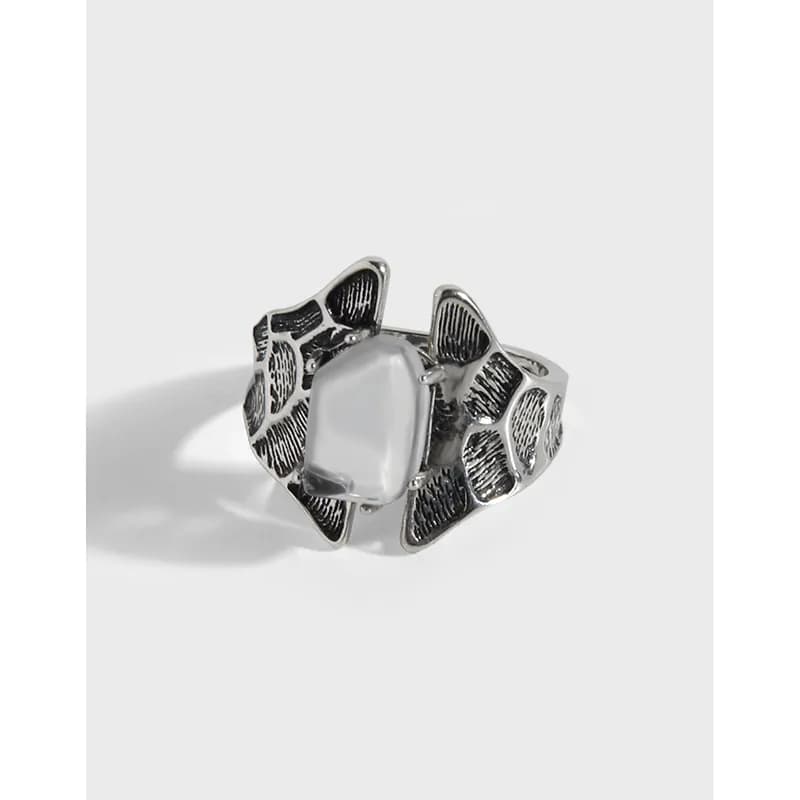 Polished sterling silver ring with a central pale stone surrounded by petal-like panels.