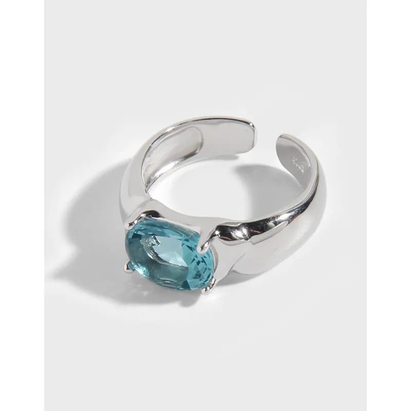 Polished sterling silver ring with an oval teal gemstone held by delicate prongs on an open curved band.