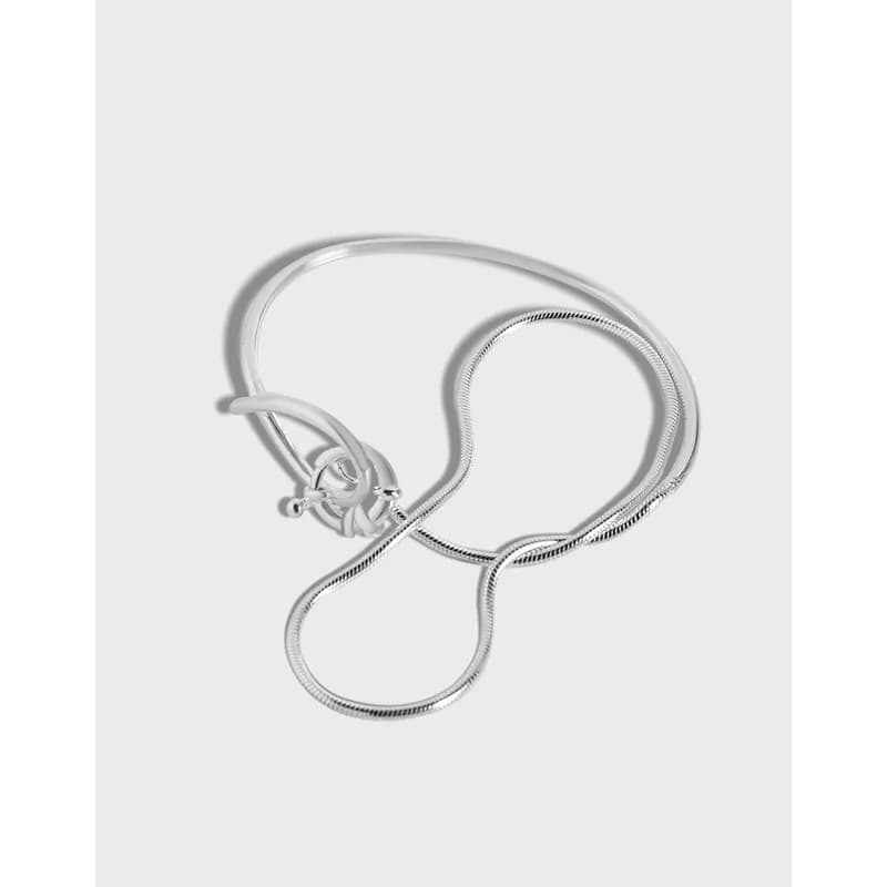 Polished sterling silver toggle ring bracelet with a curved snake-chain design on a light gray background.