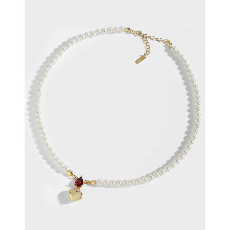 Polished sterling silver pearl necklace with a small gold heart charm and red stone pendant