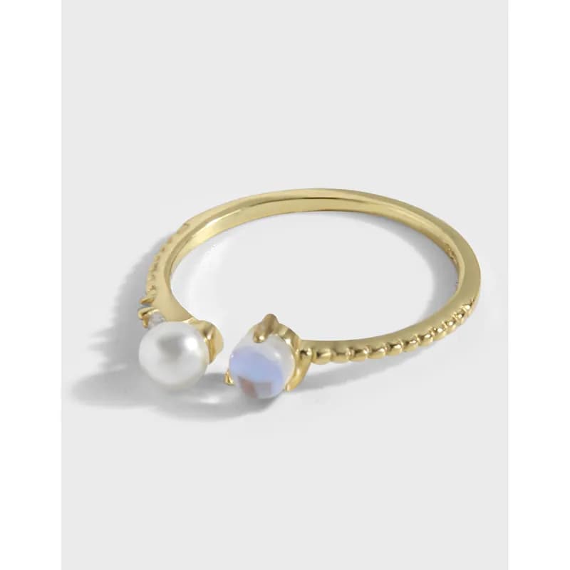 Polished sterling silver ring with two bead accents, pearl and iridescent bead, on a white background.
