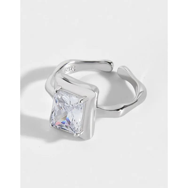 Polished sterling silver ring with a square-cut gemstone held in a squared bezel and a sculpted, wavy band.