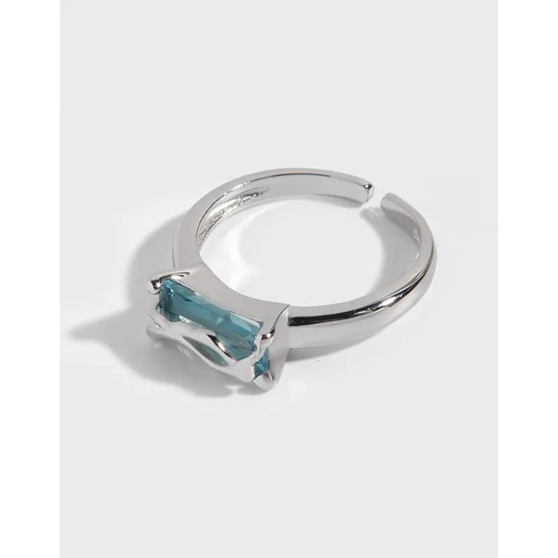 Polished sterling silver ring with a rectangular blue stone held by four prongs on the top of the band.