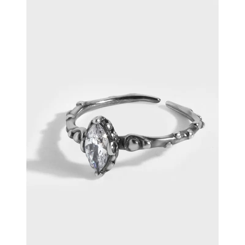 Polished sterling silver ring with a marquise-cut clear stone in a sculpted, beaded band.