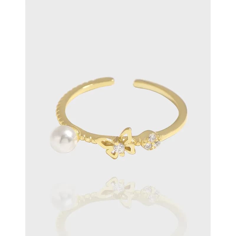 Open adjustable ring in polished sterling silver with a pearl on one end and a delicate bow plus small stones on the band.