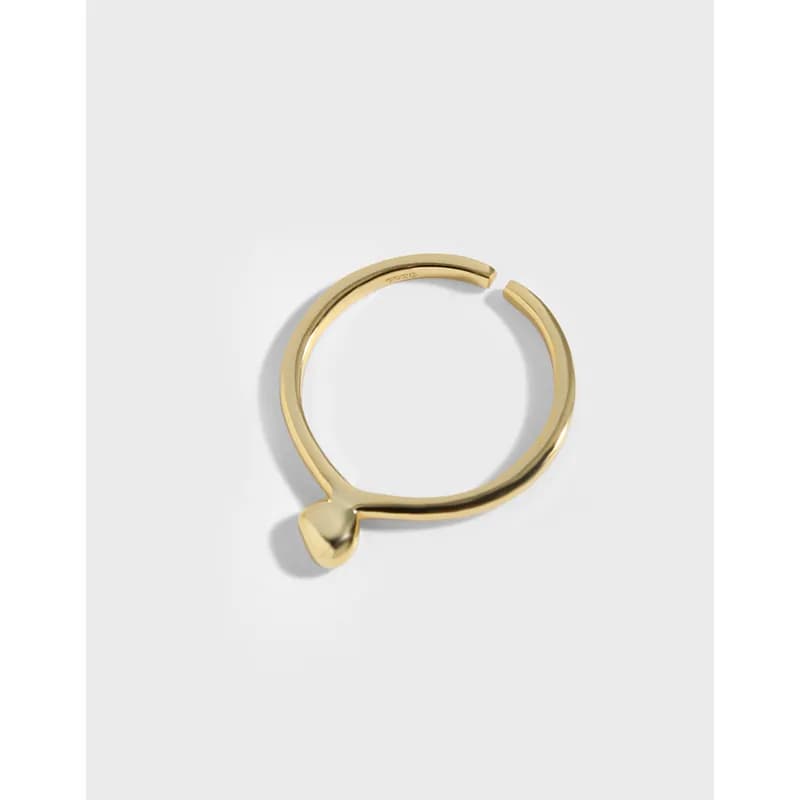 Polished sterling silver open-ring with a tiny heart detail on a light background.
