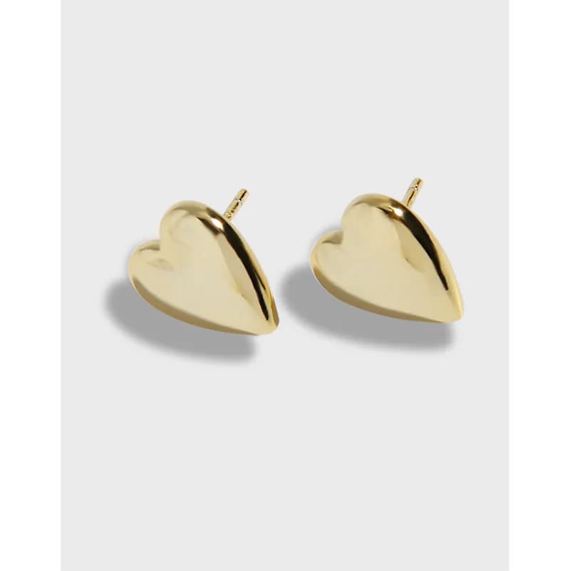 Two polished heart-shaped stud earrings with posts against a light background.