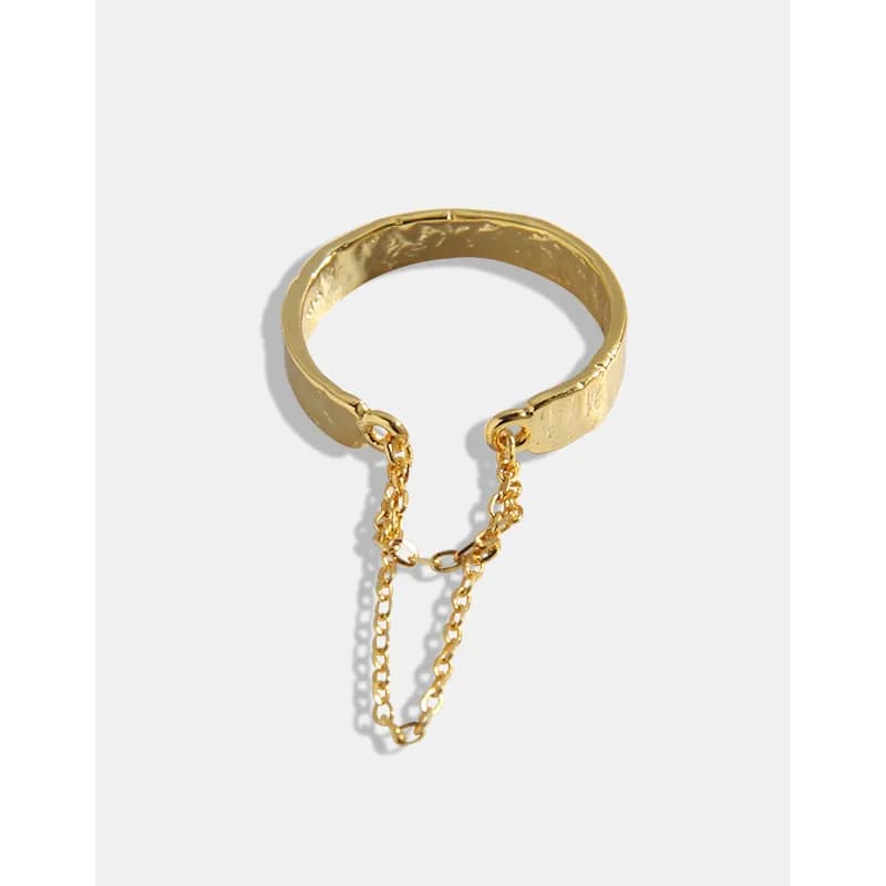 Polished ring with a dangling gold-tone chain accent attached to the band against a white background.