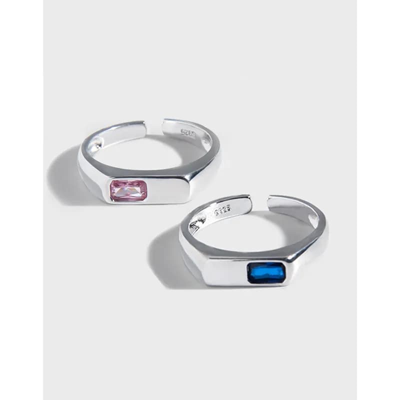Two polished sterling silver rings with rectangular bezel-set pink and blue gemstones on a smooth, squared-off band.