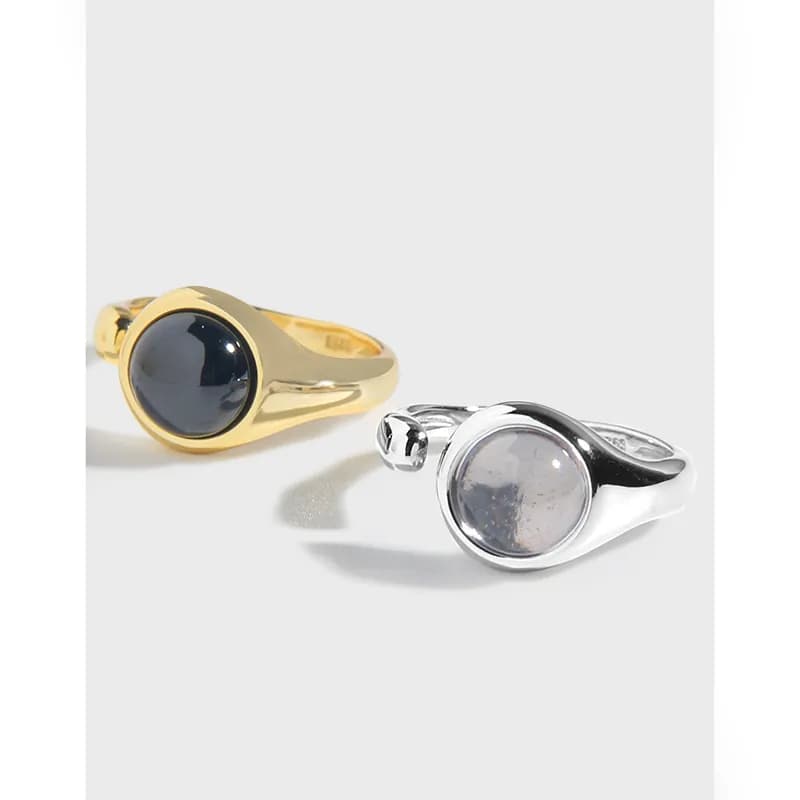Two minimalist rings with round cabochon stones in gold-tone and silver-tone settings