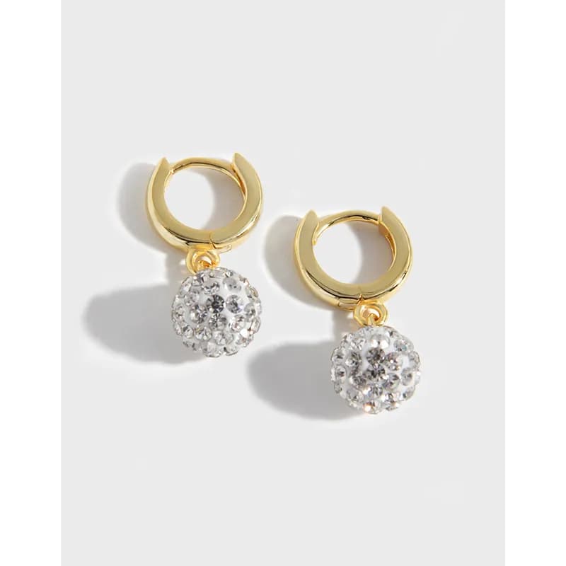 Polished gold-tone hoop earrings with crystal ball drop charms hanging from a white background.