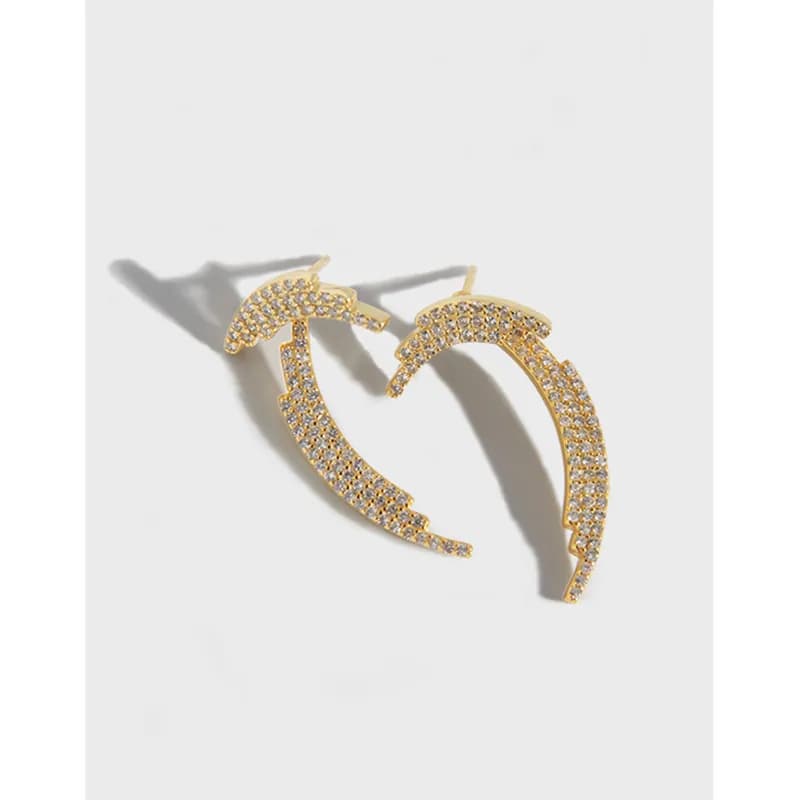 Polished sterling silver pavé crescent hoops lying on a pale surface