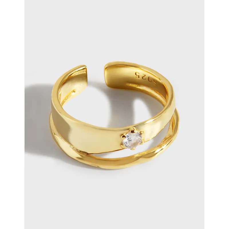 Gold-tone double-band ring with a single prong-set gemstone on one band, shown in a close-up profile view.